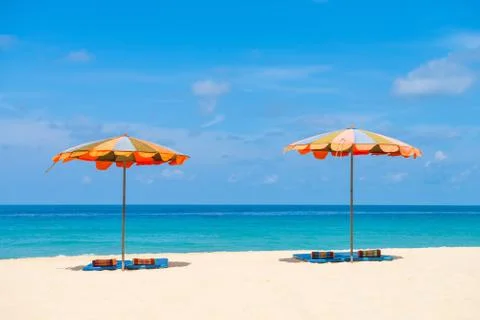 Two empty sunbeds and beach parasol sunshades on sand beach Fotos de archivo