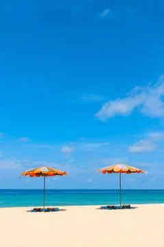 Two empty sunbeds and beach parasol sunshades on sand beach Stock Photos