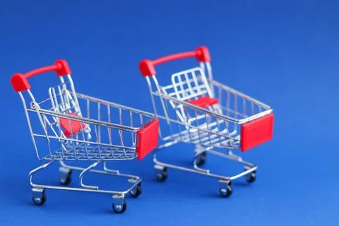 Two empty supermarket trolleys on a blue background, concept sale Stock Photos