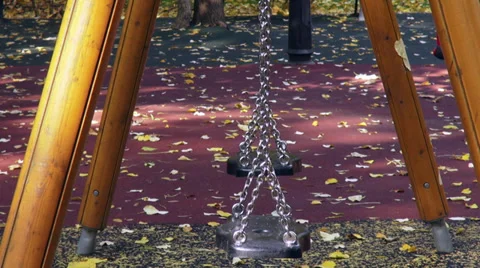 Two empty swings moving on the playground, autumn leaves, fall season Stock Footage 35599063