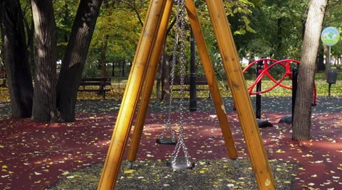 Two empty swings moving on the playground, autumn leaves, fall season Stock Footage 35599147