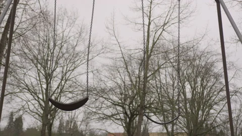 Two Empty Swings Moving on a Swing Set in an Empty Playground on a Cloudy Day 스톡 동영상 208764695