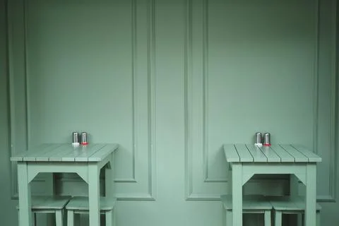 Two empty tables against a green wall in a cafe Stock Photos