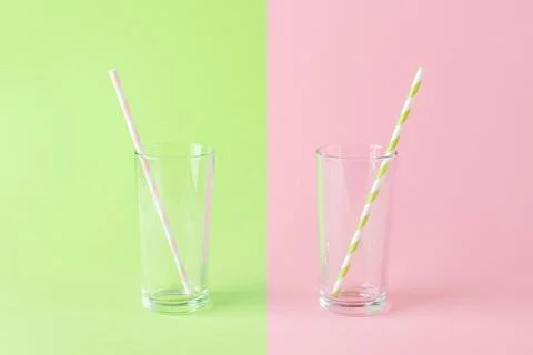 Two empty tall glasses with paper drinking straws on a green pink background. Stock Photos
