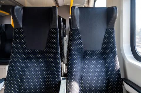 Two empty train seats are visible with sunlight coming through the window. Stock Photos