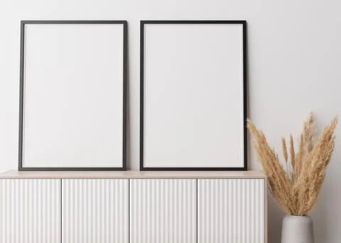 Two empty vertical picture frames standing on wooden sideboard. Mock up int.. Stock-Fotos