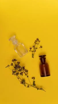 Two empty vials and dried origano flowers on yellow background. Stock Photos