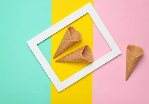 Two empty waffle horns in a white rectangular frame on a colored pastel backg Foto stock