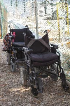 Two empty wheelchairs in front of each other on the beach on a sunny day. Stock Photos