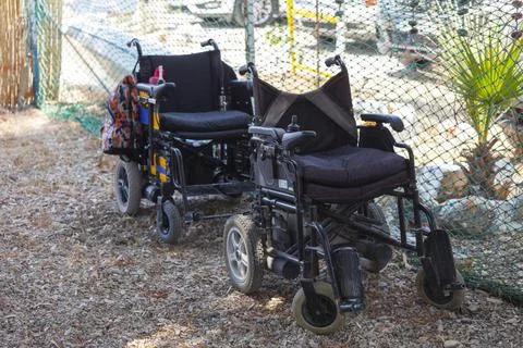 Two empty wheelchairs on the sand in front of each other. Stock Photos