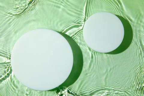 Two empty white circle podium on transparent green water background Stock Photos