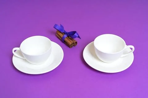 Two Empty White Cups with Cinnamon Sticks on a Purple Background Stock Photos