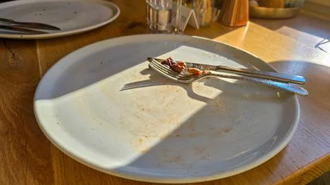 A two empty white pizza plates on a wooden table after a delicious lunch or Stock Photos