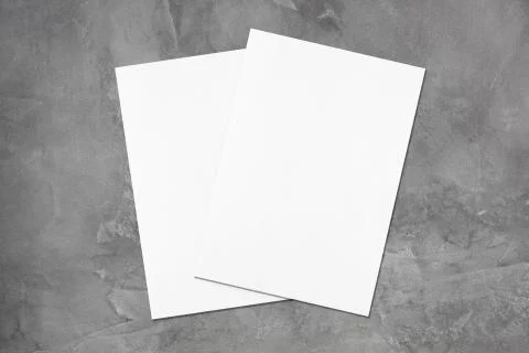 Two empty white poster mockups lying diagonally on dark grey concrete backgro Stock Photos