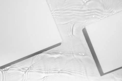 Two empty white square podium on transparent clear water background Stock Photos