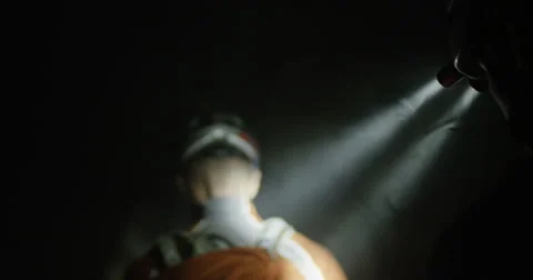 Two enduro racers navigating a dark smoky cave in slow motion follow shot Stock Footage 64683554