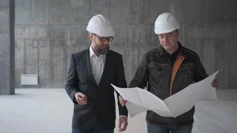 Two Engineer In Helmets With Tablet Device And Big Paper Drawings Discussing Видео 106872163