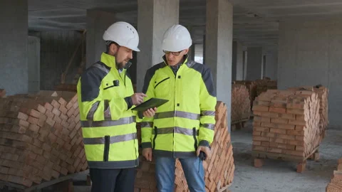 Two Engineer In Helmets With Tablet Device And Big Paper Drawings Discussing Stock Footage 113121470