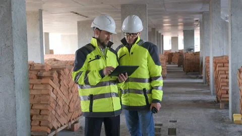 Two Engineer In Helmets With Tablet Device And Big Paper Drawings Discussing Stock Footage 113121664