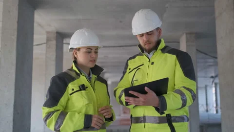 Two Engineer In Helmets With Tablet Device And Big Paper Drawings Discussing Stock Footage 113348349