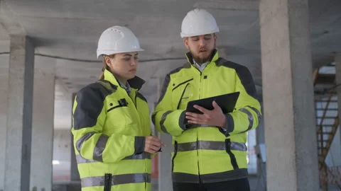Two Engineer In Helmets With Tablet Device And Big Paper Drawings Discussing Stock Footage 113348515