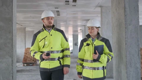Two Engineer In Helmets With Tablet Device And Big Paper Drawings Discussing Stock Footage 113349747