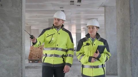 Two Engineer In Helmets With Tablet Device And Big Paper Drawings Discussing Stock Footage 113350579