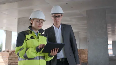 Two Engineer In Helmets With Tablet Device And Big Paper Drawings Discussing Stock Footage 113351150