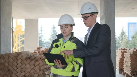 Two Engineer In Helmets With Tablet Device And Big Paper Drawings Discussing Stock Footage 113351367