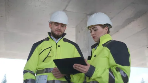 Two Engineer In Helmets With Tablet Device And Big Paper Drawings Discussing Видео 113352245