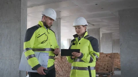 Two Engineer In Helmets With Tablet Device And Big Paper Drawings Discussing Stock Footage 113352314
