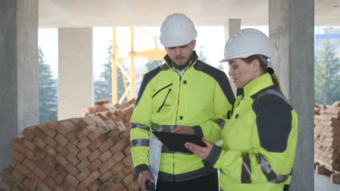 Two Engineer In Helmets With Tablet Device And Big Paper Drawings Discussing Stock Footage 113352443
