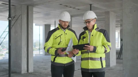 Two Engineer In Helmets With Tablet Device And Big Paper Drawings Discussing Stock Footage 113352796