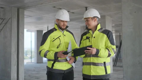 Two Engineer In Helmets With Tablet Device And Big Paper Drawings Discussing Stock Footage 113352827