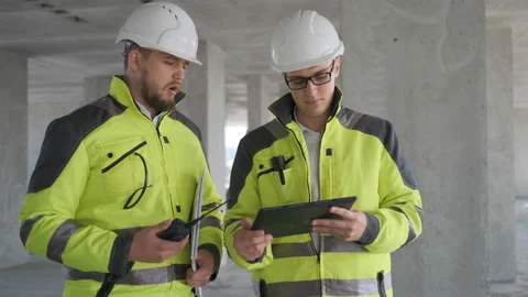 Two Engineer In Helmets With Tablet Device And Big Paper Drawings Discussing Stock Footage 113352968