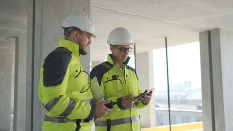 Two Engineer In Helmets With Tablet Device And Big Paper Drawings Discussing Stock Footage 113352984