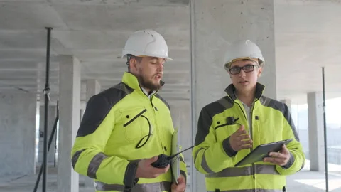 Two Engineer In Helmets With Tablet Device And Big Paper Drawings Discussing Stock Footage 113353129