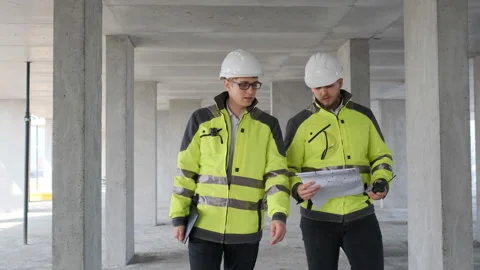 Two Engineer In Helmets With Tablet Device And Big Paper Drawings Discussing Stock Footage 113353250