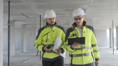 Two Engineer In Helmets With Tablet Device And Big Paper Drawings Discussing Stock Footage 113353358