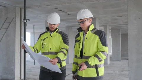 Two Engineer In Helmets With Tablet Device And Big Paper Drawings Discussing Stock Footage 113353551