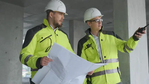 Two Engineer In Helmets With Tablet Device And Big Paper Drawings Discussing Stock Footage 113353608
