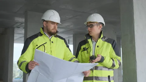 Two Engineer In Helmets With Tablet Device And Big Paper Drawings Discussing Stock Footage 113353667