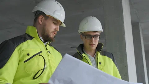 Two Engineer In Helmets With Tablet Device And Big Paper Drawings Discussing Stock Footage 113353699