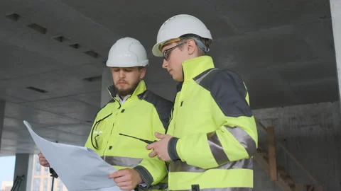 Two Engineer In Helmets With Tablet Device And Big Paper Drawings Discussing Stock Footage 113353820
