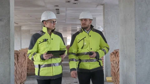 Two Engineer In Helmets With Tablet Device And Big Paper Drawings Discussing Stock Footage 113354458