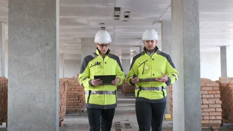 Two Engineer In Helmets With Tablet Device And Big Paper Drawings Discussing Stock Footage 113354533