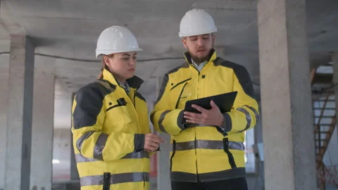 Two Engineer In Helmets With Tablet Device And Big Paper Drawings Discussing Video stock 114529751