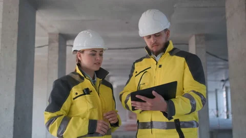 Two Engineer In Helmets With Tablet Device And Big Paper Drawings Discussing Video stock 114529754