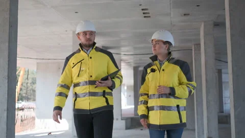 Two Engineer In Helmets With Tablet Device And Big Paper Drawings Discussing Video stock 114529926