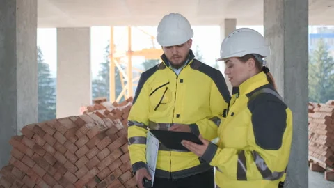 Two Engineer In Helmets With Tablet Device And Big Paper Drawings Discussing Video stock 114536310